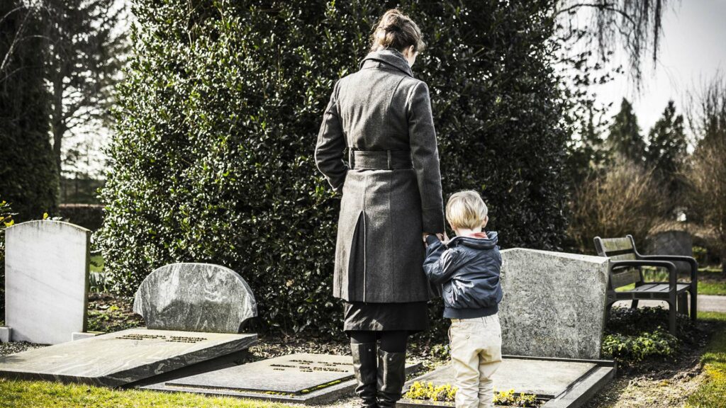 image of woman and son looking at the grave of their family member, a police officer killed in the line of duty